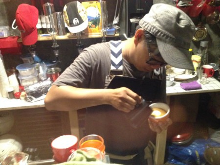 Izman religiously pouring a latte art on a cappuccino.
